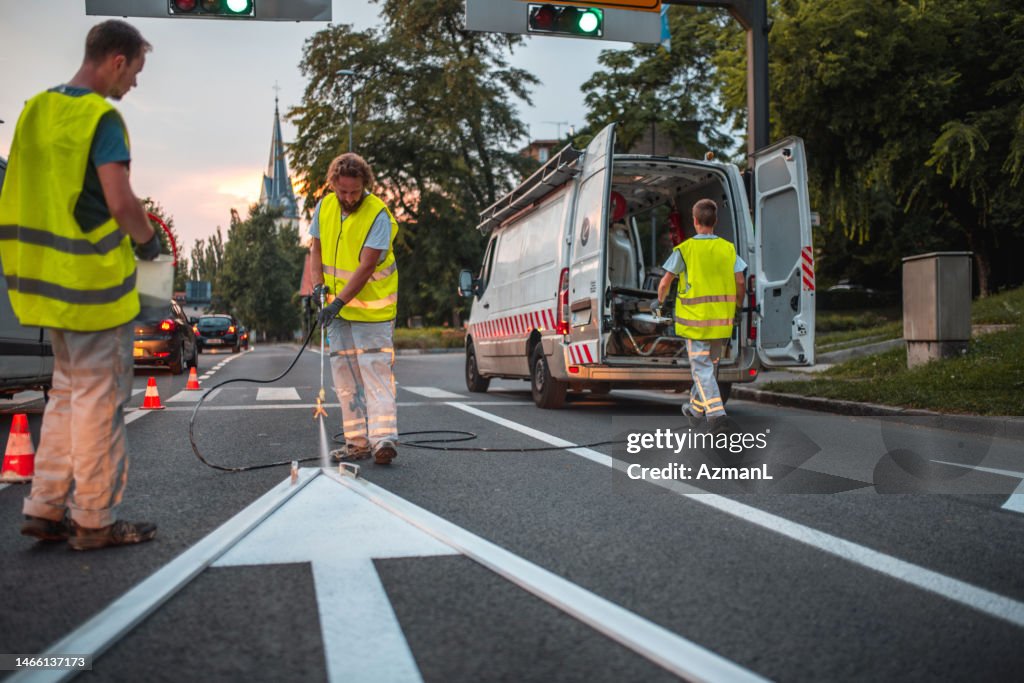 Road Maintenance Crew Repainting A Forward Pointing Arrow Road Sign