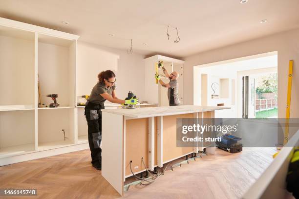 kitchen fitters installing some cabinets - renovatie begrippen stockfoto's en -beelden