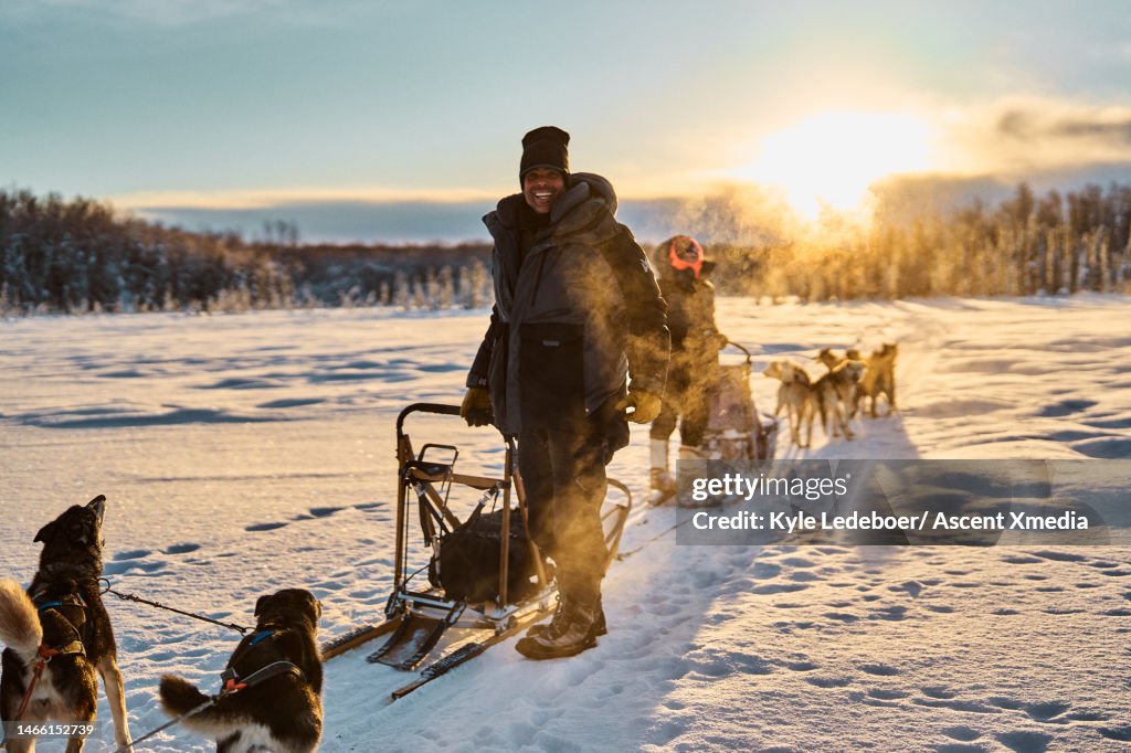 Dog mushers pause with teams on snowy track