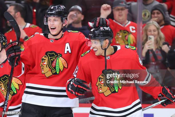 Caleb Jones of the Chicago Blackhawks celebrates with Connor Murphy after scoring a game-winning goal in overtime against the Arizona Coyotes at...
