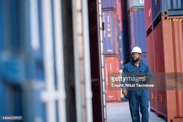technology is helping ports optimize their operations in global containerization services. african american male transport engineer walking with holding a tablet computer to examine cargo in a commercial dock. - supply chain stock pictures, royalty-free photos & images