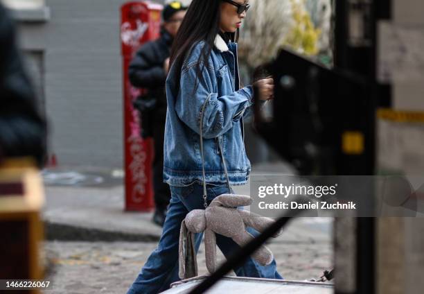 Guest is seen wearing a jean jacket, denim pants and a diamond stuffed bunny bag outside the Hellessy show during New York Fashion Week F/W 2023 on...