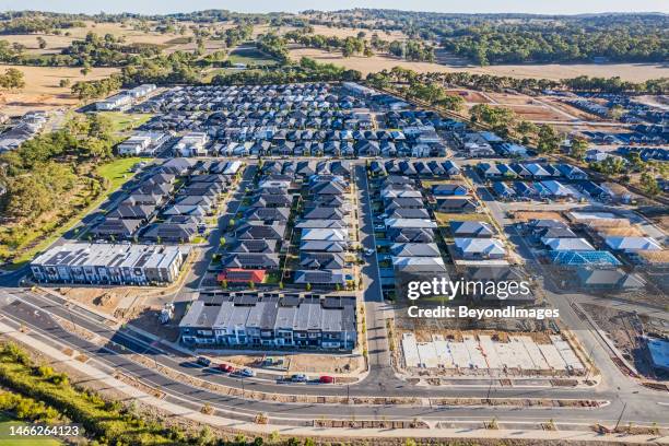 ein rotes dach zwischen häuserreihen verschiedener baustile mit grautönen in ländlicher zersiedelung. - australian community stock-fotos und bilder