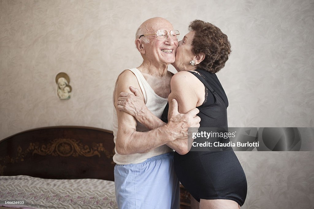 Happy elderly couple hugging in a bedroom