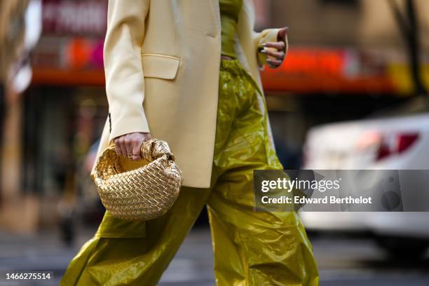 Leonie Hanne wears a beige oversized blazer jacket, a green shoulder off / cropped top, green silk satin large cargo pants, a gold shiny leather...