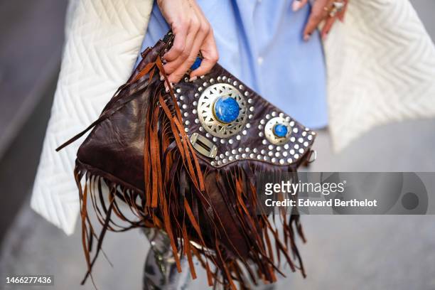 Ghizlane Sabbahe wears a pale blue shirt knees dress, a white latte quilted pattern oversized coat, a brown shiny leather with embroidered silver...