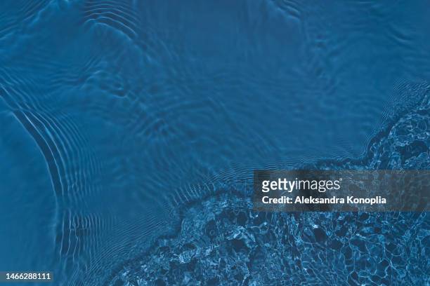 dark pastel navy blue transparent clear water surface texture with ripples, splashes and waves in sunlight - drink dark background stockfoto's en -beelden