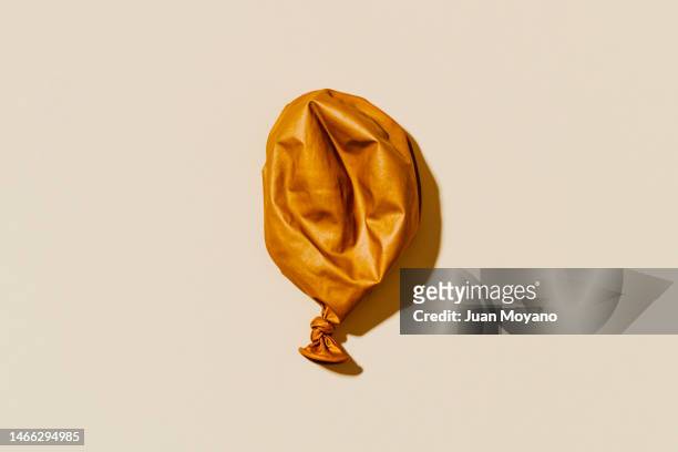 high angle view of a deflated golden balloon - deflated stock-fotos und bilder