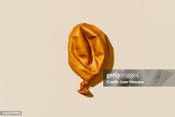 high angle view of a deflated golden balloon - after party garbage stock pictures, royalty-free photos & images