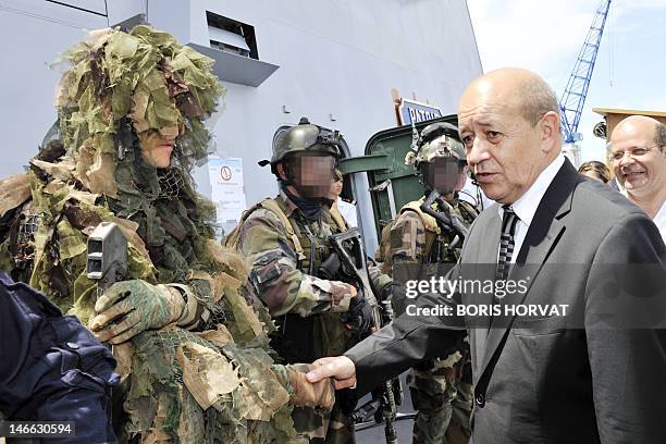 France's Defence Minister Jean-Yves Le Drian shakes hands with members of the French Navy commando Hubert during his visit on board of the French...