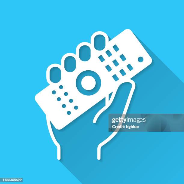 hand holding up remote control. icon on blue background - flat design with long shadow - holding remote control stock illustrations