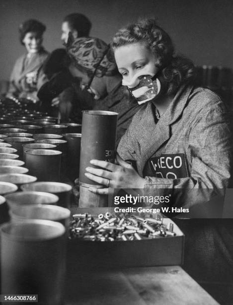 Female factory worker wears a protective mask whilst assembling a Wessex Daylight Smoke Signal distress flare canister at a Ministry of Supply...
