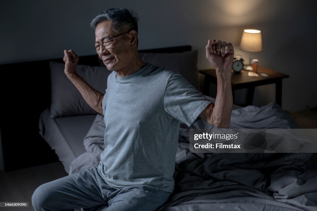 Senior Asian man suffering from back ache on the bed, healthcare and problem concept