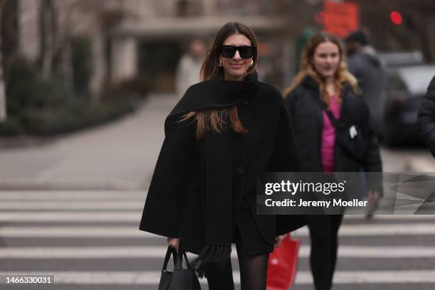 Guest is seen wearing Bottega Veneta Drop gold earrings, black sunglasses, Toteme black oversize scarf wool jacket, black tights and a black leather...