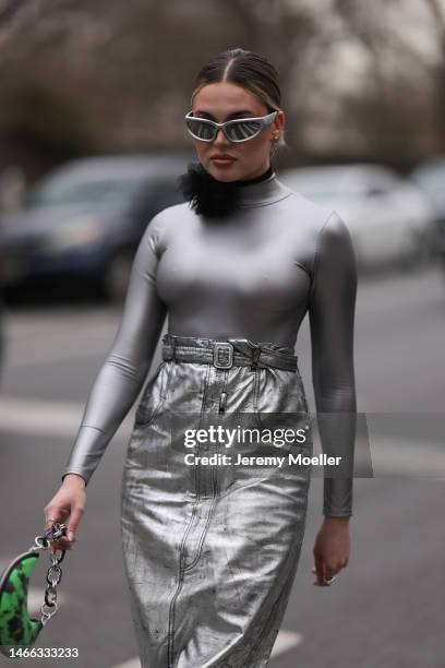 Guest seen wearing Balenciaga silver sunglasses, silver earrings, black choker necklace with a tulle flower, shiny silver turtleneck top with long...