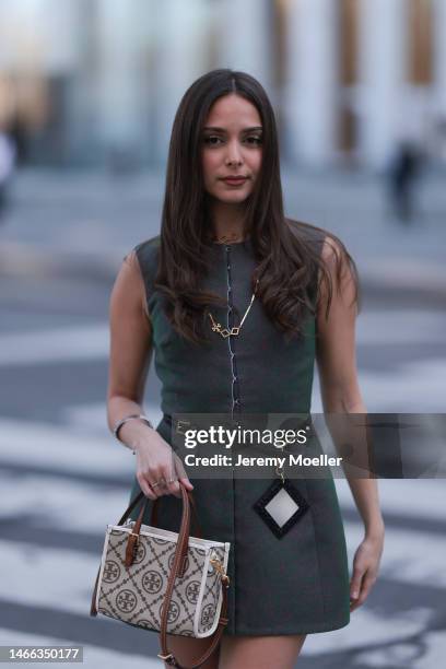 Andrea Sabotic seen wearing Tory Burch gold necklace, silver bracelet, Tory Burch grey sleeveless short dress, Tory Burch black leather belt with a...