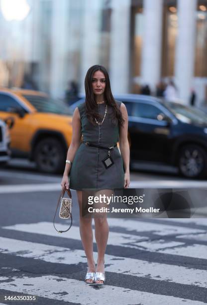 Andrea Sabotic seen wearing Tory Burch gold necklace, silver bracelet, Tory Burch grey sleeveless short dress, Tory Burch black leather belt with a...