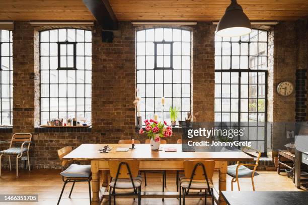 dining table in modern loft apartment warehouse conversion - table brick wall wood stockfoto's en -beelden