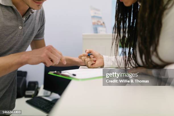 close-up of patient filling documents at the clinic reception - long form stock pictures, royalty-free photos & images