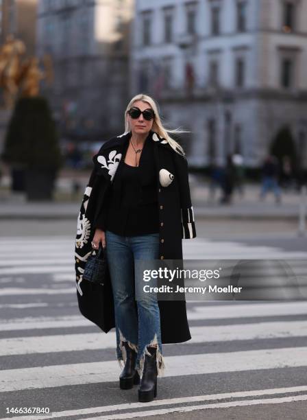 Corina Mihaila Larpin seen wearing Linda Fargo black sunglasses, Schiaparelli black long coat with white ornament print pattern, R13 dark blue...