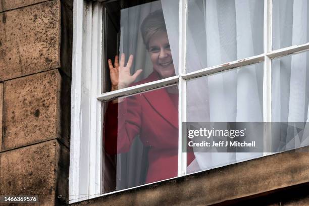 Nicola Sturgeon waves from a window, after holding a press conference, as people gather outside of Bute House on February 15, 2023 in Edinburgh,...