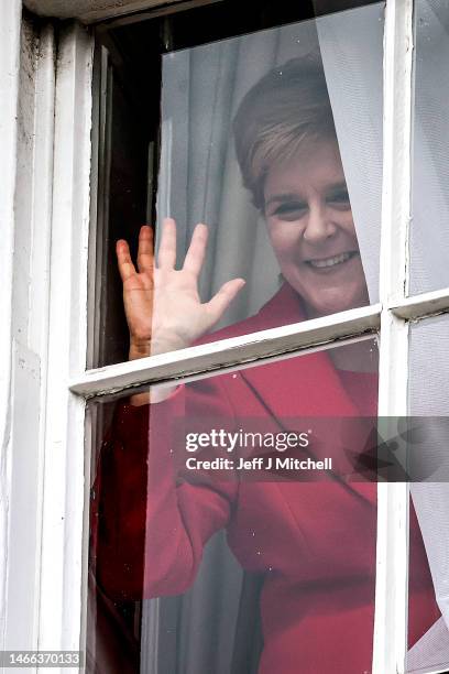 Nicola Sturgeon waves from a window, after holding a press conference, as people gather outside of Bute House on February 15, 2023 in Edinburgh,...