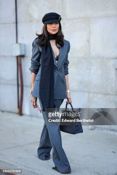 Guest wears black felt wool beret cap from Chanel, a black wool scarf, a gray striped print pattern blazer jacket, matching gray striped print...