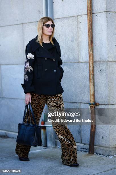 Guest wears black sunglasses, a black t-shirt, a black with embroidered beige and pink flower pattern buttoned jacket, beige and black leopard print...