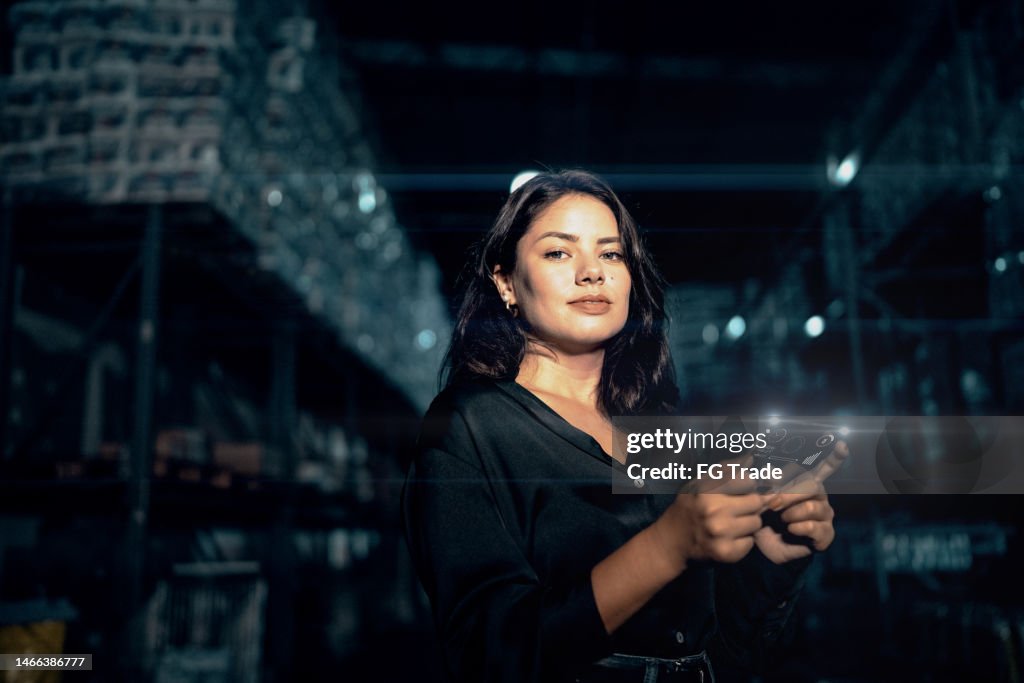 Portrait of a young woman analyzing graphs on digital intelligence in a warehouse