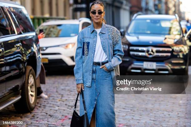 Tamara Kalinic wears denim jacket with rhinestones, denim skirt with slit, Prada bag, pointed heels sunglasses outside Hellessy during New York...