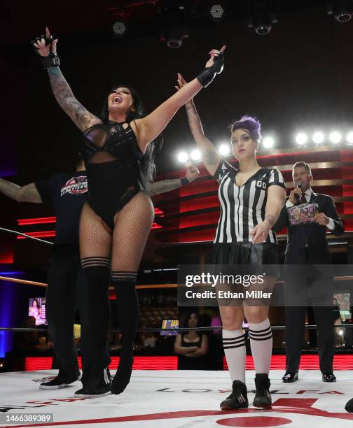 Referee Sarah Wolfe raises the arm of Katie "The Bombshell" Forbes as host and ring announcer A.J. Kirsch announces her victory over Salina de la...