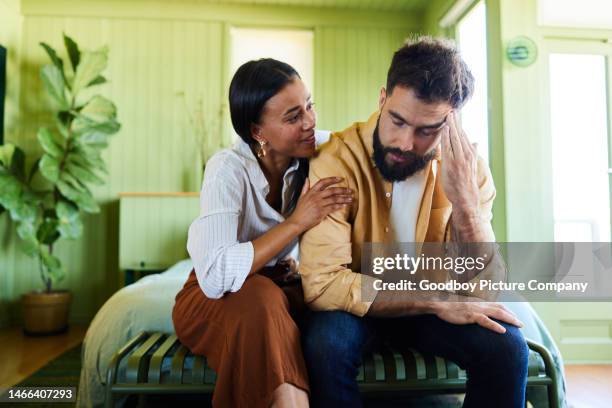 自宅の寝室で動揺した夫を慰める若い女性 - 勃起障害 ストックフォトと画像