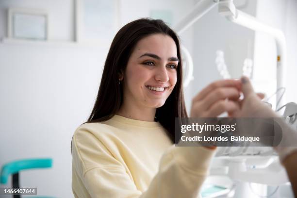 teen girl puts on transparent braces at the dentist - bruxism stock pictures, royalty-free photos & images