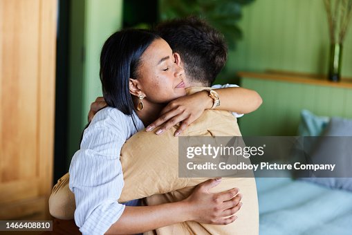 Loving woman hugging her upset husband in their bedroom at home