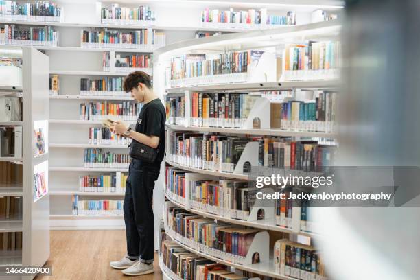 young man taking books in a library. - singapore school stock-fotos und bilder