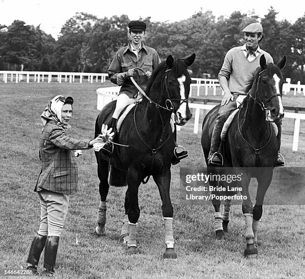 Queen Elizabeth II with her daughter Princess Anne and Anne's husband Mark Phillips on the racecourse at Ascot, 18th June 1976.