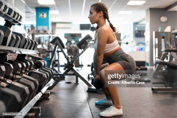 a woman exercising with dumbbells at the gym - agachar se imagens e fotografias de stock