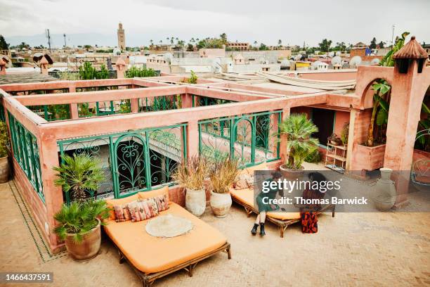 wide shot of smiling sisters relaxing on lounge chair on hotel rooftop - arab family in hotel stock-fotos und bilder