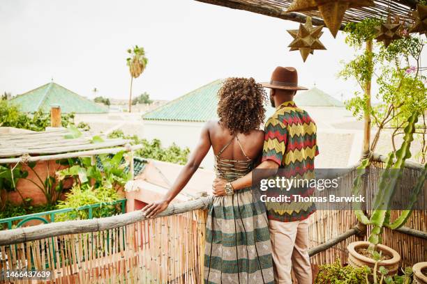 medium shot of embracing couple looking at view from hotel rooftop - black couple dining stockfoto's en -beelden