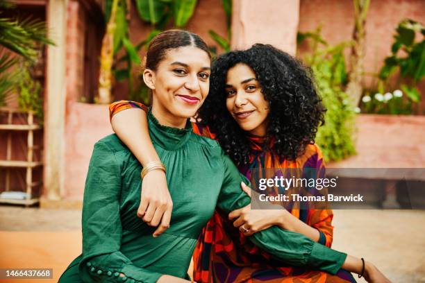 medium shot of smiling embracing sisters relaxing on hotel rooftop - arab woman portrait stockfoto's en -beelden