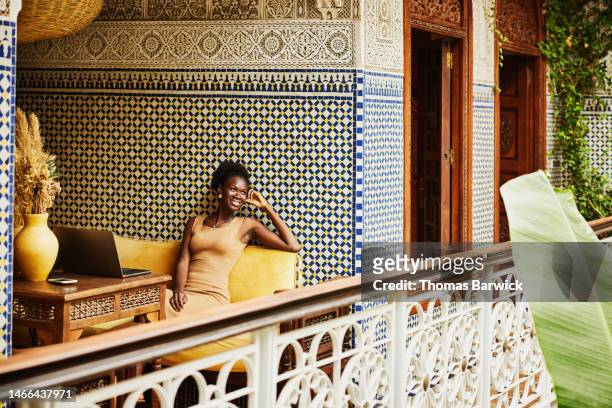 wide shot woman relaxing while working on laptop in alcove of riad - morocco tourist stock pictures, royalty-free photos & images