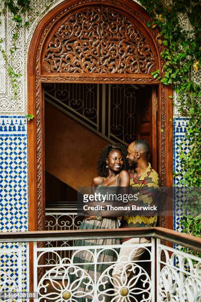 Wide shot smiling couple in doorway of ornately decorated riad