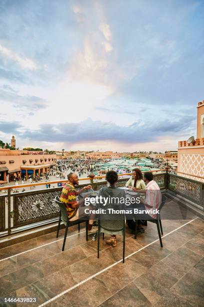 wide shot friends sharing meal at rooftop restaurant during vacation - exclusive event stock pictures, royalty-free photos & images