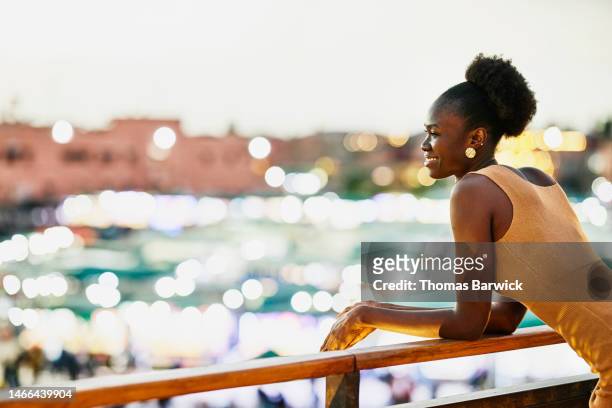 medium shot woman looking at jamaa el fna square from rooftop restaurant - self tan stock pictures, royalty-free photos & images