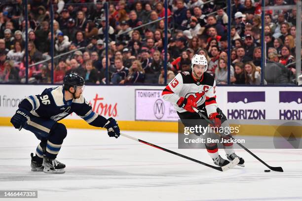 Nico Hischier of the New Jersey Devils skates with the puck as Jack Roslovic of the Columbus Blue Jackets defends during the second period of a game...