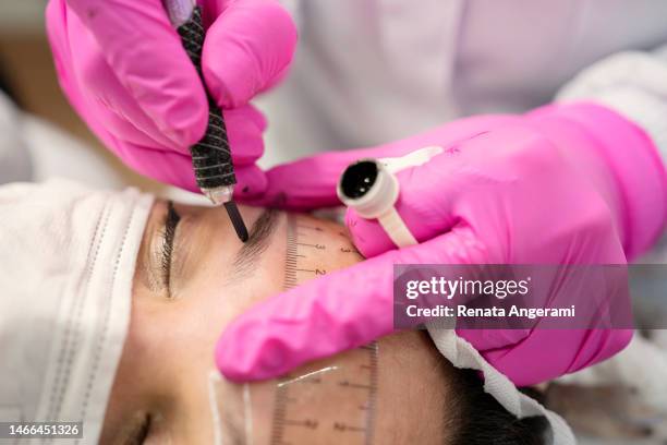 esthéticienne effectuant une technique de microblading dans le sourcil du client. micropigmentation fil par fil - maquillage permanent photos et images de collection