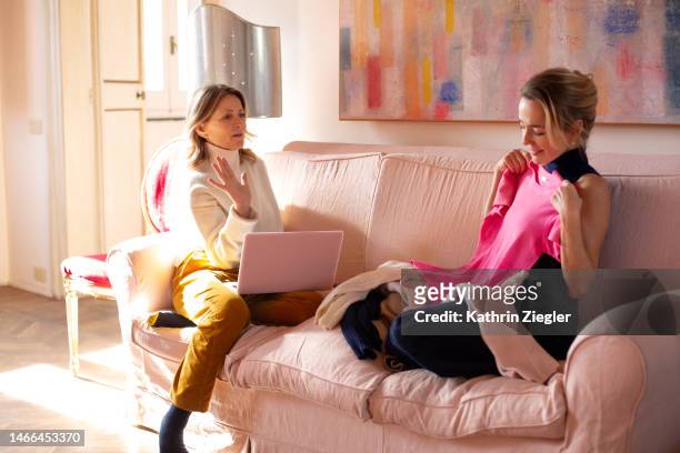 two women sitting on sofa with laptop, looking at cashmere products - only mature women stock pictures, royalty-free photos & images