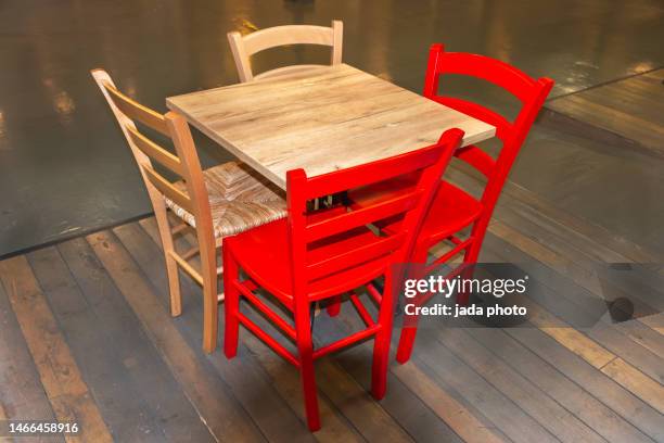 wooden table with two red wooden chairs and two wicker chairs - casual low view desk cafe stockfoto's en -beelden