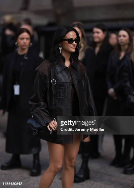 Camila Mendes seen wearing a dark brown leather jacket and a black bag by Coach before the Coach show on February 13, 2023 in New York City.