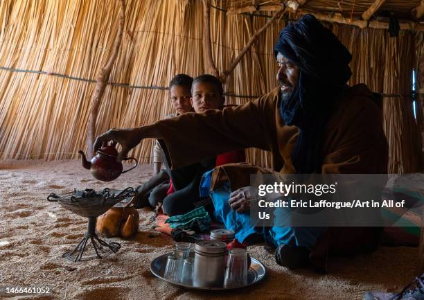 Tuareg man and children inside a reeed house preparing tea, North Africa, Tamanrasset, Algeria on December 27, 2022 in Tamanrasset, Algeria.